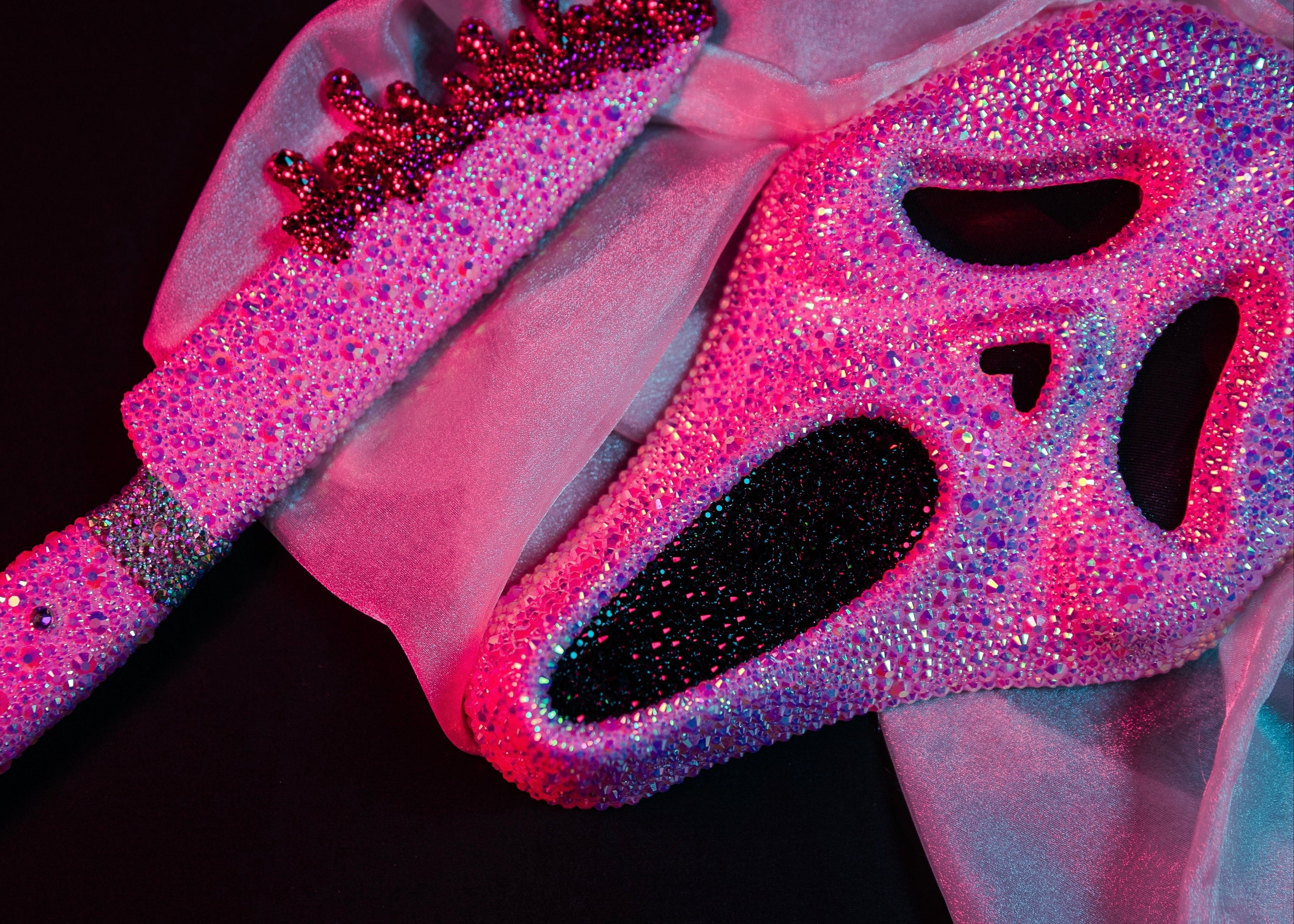 Pink rhinestone mask with matching blade on a dark background